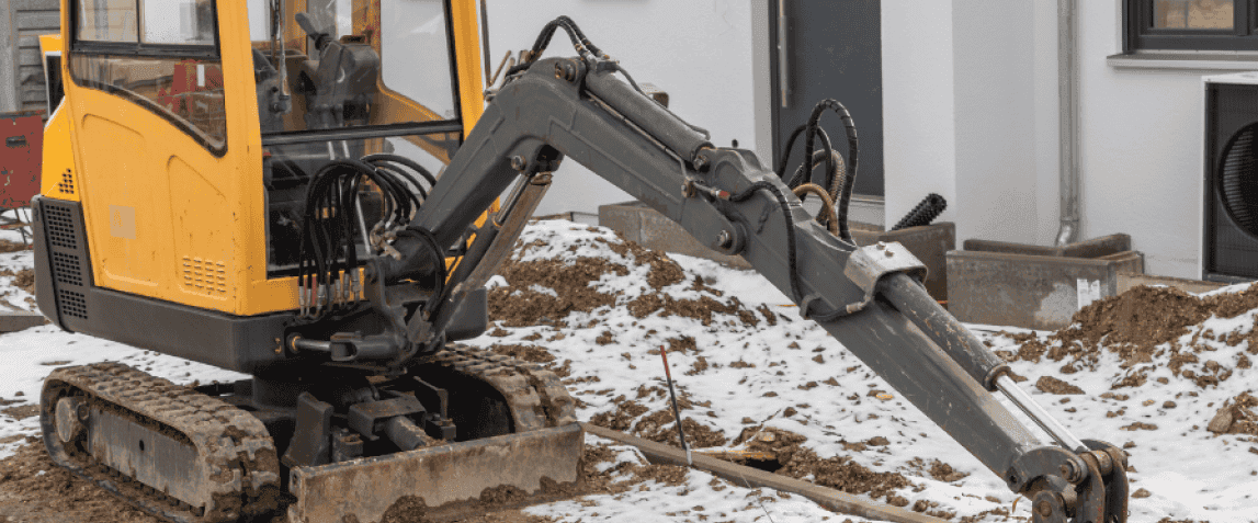 en-gul-gravmaskin-som-graver-ett-hal-i-en-snöig-miljö